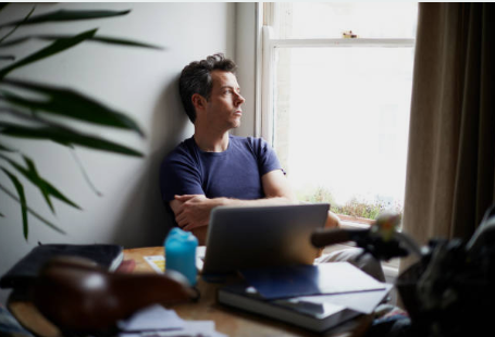 Person sitting quietly by a window, looking emotionally drained but composed.